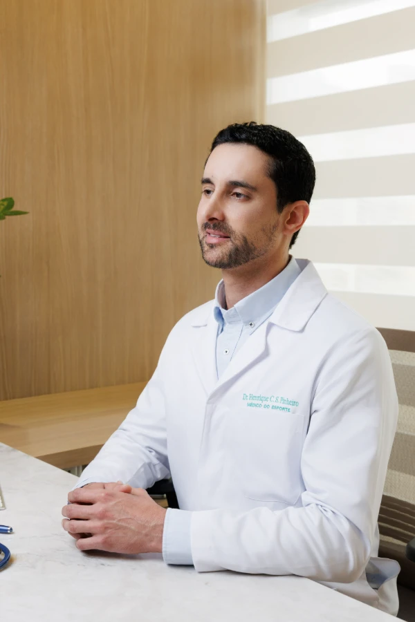 Dr. Henrique Pinheiro sentado à mesa do consultório